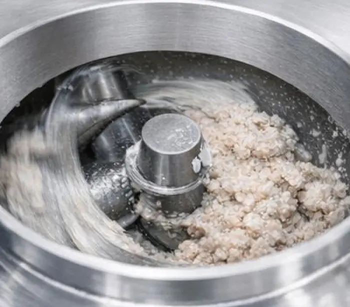 Fish mixture being processed in a stainless steel grinder