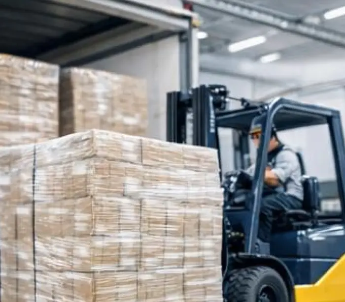 Forklift moving palletized fish treat cartons in a warehouse